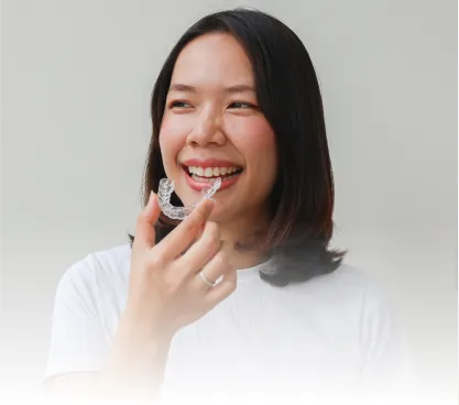 Woman holding a clear aligner up to their mouth